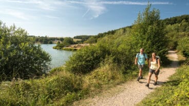 Zwei Wanderer auf dem AhrSteig gehen am Freilinger See vorbei