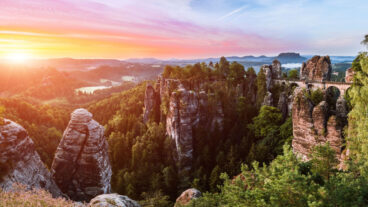 Ein Blick auf die Basteibrücke vom Ferdinandsaussicht mit einem Sonnenaufgang über dem Nationalpark Sächsische Schweiz