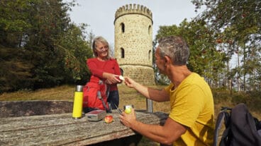 Zwei Wanderer machen an einem Rastplatz an einem Tisch vor dem Bierbaums Nagel Pause