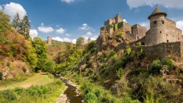 Die Lieser fließt an den Burgruinen Oberburg und Niederburg in Manderscheid vorbei